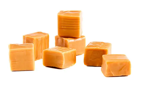 Photo of Unwrapped caramel candies on a white background