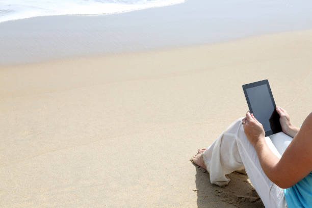 istock One woman only using digital tablet on the beach. 1174811488