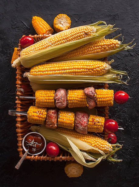 黒い暗い背景にトウモロコシと肉のシシケバブ。野菜の揚げ物トウモロコシ トマト コショウローストした肉焼き野菜。 トップビュー - kebab apple pork bacon ストックフォトと画像