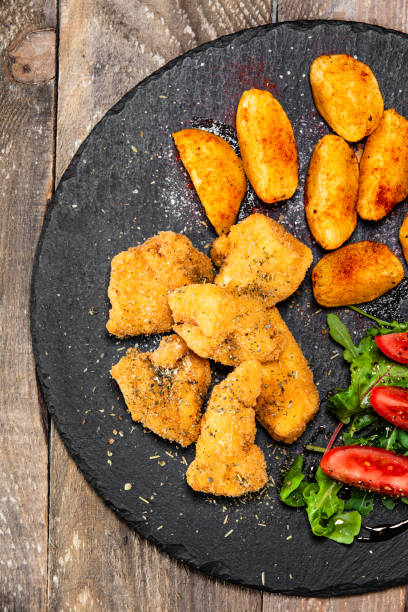 istock Fried chicken nuggets with baked potatoes and vegetables 1174815146