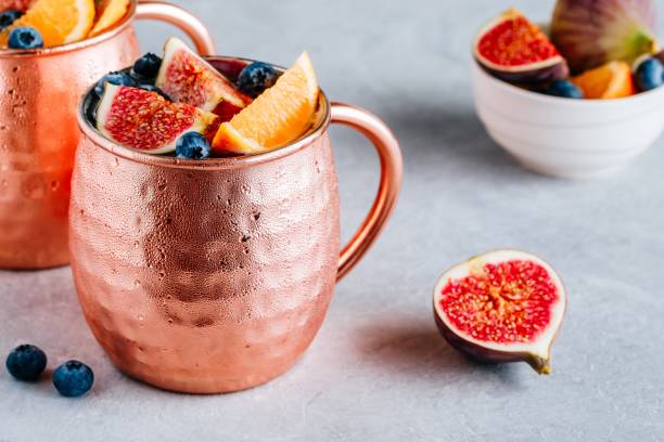 istock Fig Moscow mule ice cold cocktail in copper cup with blueberries and orange 1174818921