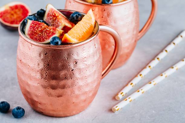 istock Fig Moscow mule ice cold cocktail in copper cup with blueberries and orange 1174818972