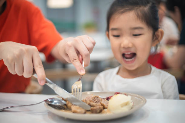 Mother helps her daughter to divide food Mother helps her daughter to divide food chinese ethnicity china restaurant eating stock pictures, royalty-free photos & images