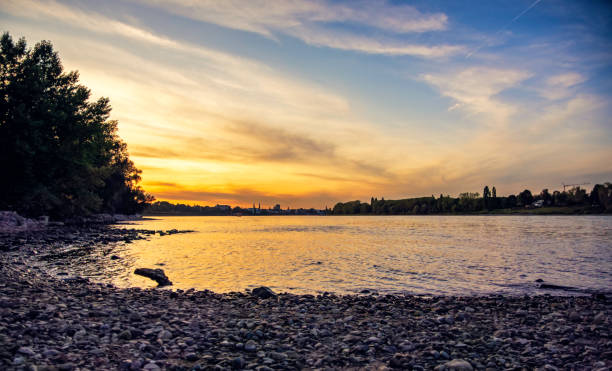 Beautiful orange sunset seen from a tiny pebbled beach by the Rheine river in Bonn.