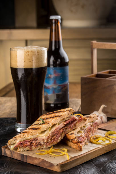 gegrilltes reuben sandwich mit dunklem bier auf holzschneidebrett - pumpernickel stock-fotos und bilder