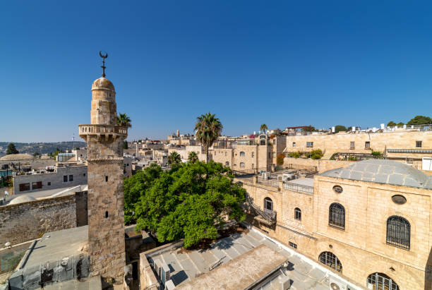 vecchio minareto tra case tipiche sotto il cielo blu nella città vecchia di gerusalemme, israele. - jerusalem israel roof looking at view foto e immagini stock
