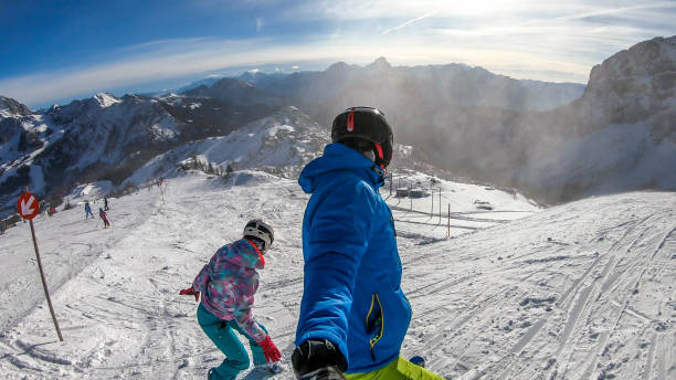 istock Nassfeld - A snowboarder and a skier going down the slope 1174823618