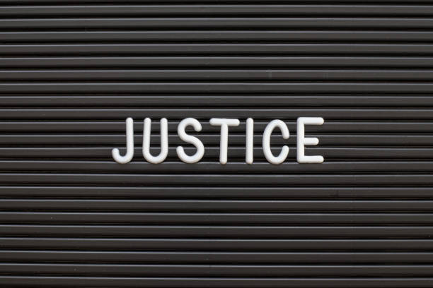 istock Black color felt letter board with white alphabet in word justice background 1174825445
