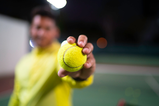 Focus on player's hand holding a tennis ball