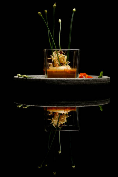 Prawn ballotine on lobster bisque. Exquisite dish. Creative restaurant meal concept. Haute couture food on black with reflection. Fine dining concept.