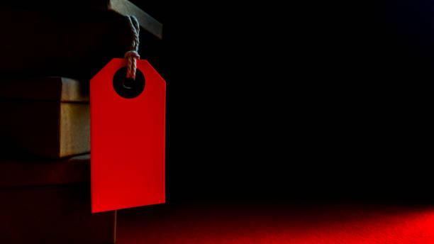 istock Cardboard boxes with a tag. Brown packing box with blank label and copy space on red backdrop 1174834066