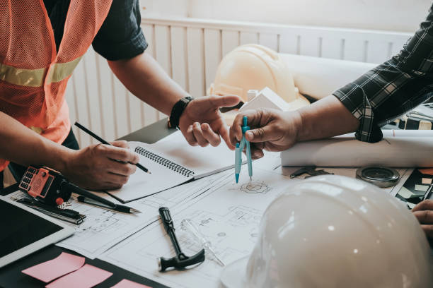 istock Engineer and contractor planning projects together at desk with blueprints. 1174841454