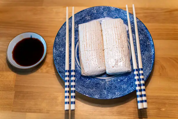Flat top view of Japanese traditional komo tofu dofu food, chopsticks and soy sauce on plate on kitchen wooden table in Takayama, Hida in Gifu prefecture