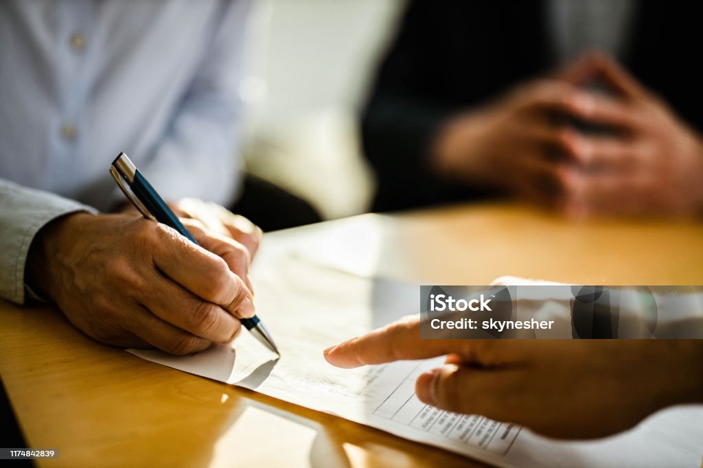 Close up of unrecognizable person signing a contract. Close up of unrecognizable female person signing a contract on a meeting with agent. Contract Stock Photo