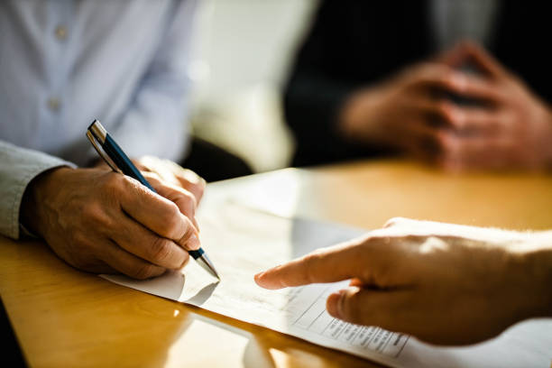 Close up of unrecognizable person signing a contract. Close up of unrecognizable female person signing a contract on a meeting with agent. mortgage document stock pictures, royalty-free photos & images