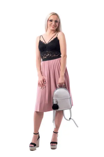 Happy smiling blond woman holding trendy faux leather gray shiny bag looking at camera. Full body isolated on white background.