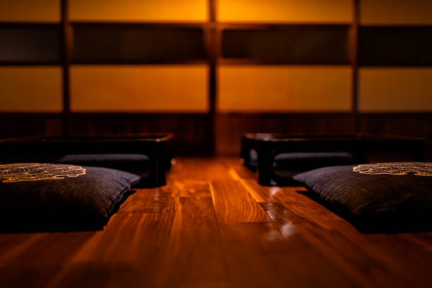 Floor level of traditional Japanese machiya house ryokan with black lacquered wooden table, cushion pillows and sliding paper doors at dark night or evening Floor level of traditional Japanese machiya house ryokan with black lacquered wooden table, cushion pillows and sliding paper doors at dark night or evening indoors restaurant hotel work tool stock pictures, royalty-free photos & images