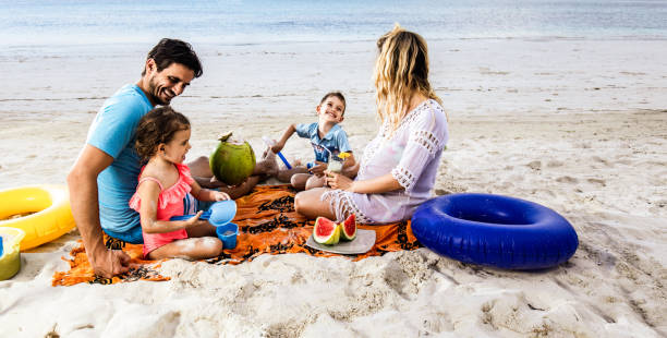 istock Happy family talking while relaxing on beach towel in summer day. 1174847520