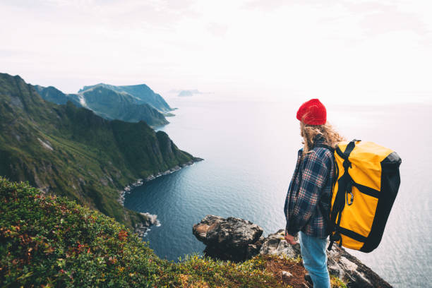 dzielny turysta podróżujący w wysokich górach nad morzem. hipster traveler z plecakiem stojącym na krawędzi skały klifu. styl życia przygoda wanderlust - rock norway courage mountain zdjęcia i obrazy z banku zdjęć