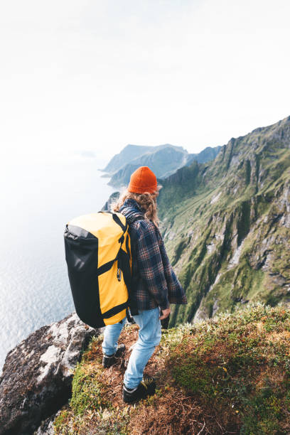 samotny profesjonalny podróżnik z plecakiem na wysokiej górze stojący na skraju klifu i patrzący w przyszłość. przygodowe wakacje w stylu życia - rock norway courage mountain zdjęcia i obrazy z banku zdjęć