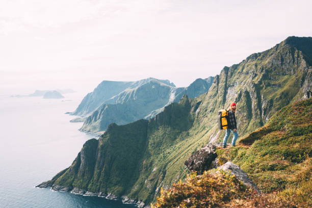 istock Alone man expeditor wearing professional backpack standing on the edge cliff mountain above sea and looking on epic high landscape. Lifestyle adventure vacation 1174848260