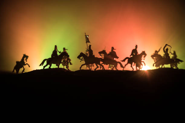 istock Medieval battle scene with cavalry and infantry. Silhouettes of figures as separate objects, fight between warriors on dark toned foggy background. Night scene. 1174856262