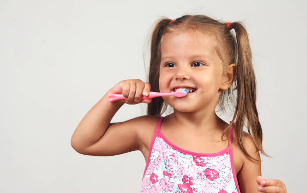 istock Little girl brushing teeth with toothbrush over white background with copy space 1174858173