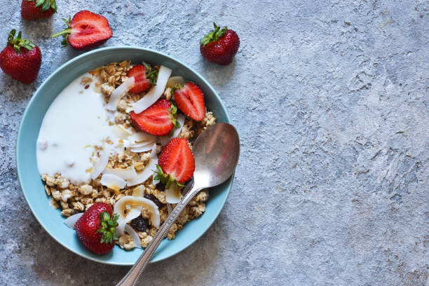 klassisches frühstück - müsli, kokoschips, griechischer joghurt und erdbeeren in einem schönen teller auf dem küchentisch. blick von oben. - oatmeal porridge oat raisin stock-fotos und bilder