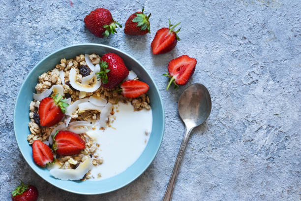 petit déjeuner classique - granola, croustilles de noix de coco, yaourt grec et fraises dans une belle assiette sur la table de la cuisine. vue plongeante. - yogurt greek culture milk healthy eating photos et images de collection