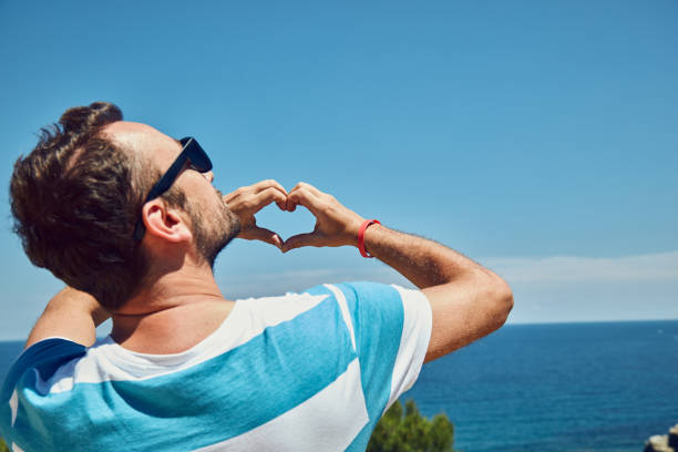 istock Man making heart shape with hands on tropical beach. 1174864617