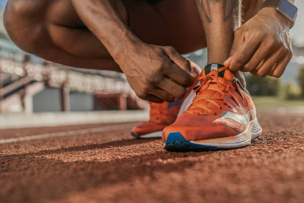 zbliżenie dłoni wiązania sznurowadła sneaker na torze. przygotowanie do joggingu. - running jogging men shoe zdjęcia i obrazy z banku zdjęć