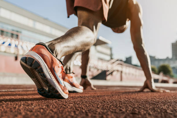 de cerca de atleta masculino preparándose para empezar a correr en la pista. concéntrese en las zapatillas - mens track fotos fotografías e imágenes de stock