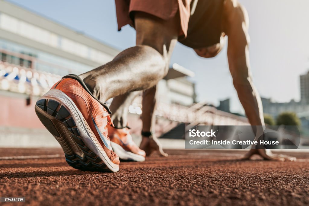 Close up of male athlete getting ready to start running on track . Focus on sneakers Running, Sport, Sprinting, Athlete, Exercising Running Stock Photo