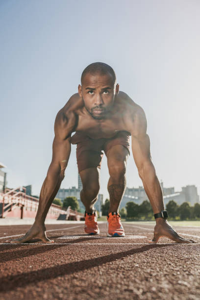 istock Front view of fit and confident man in starting position ready for running 1174864767