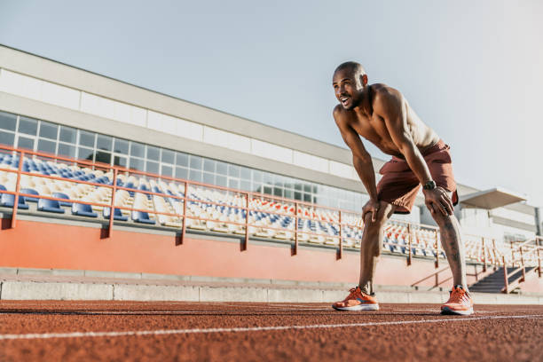 istock Male runner resting with his hands on knees standing on a running track 1174864873