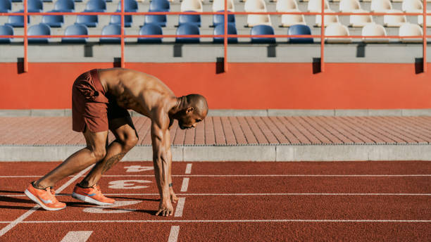 istock Side view of an athlete getting ready to start his sprint on a running track 1174864885