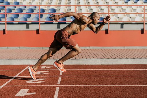 Vista lateral de un atleta que comienza su sprint en una pista de atletismo para todo tipo de tiempo photo