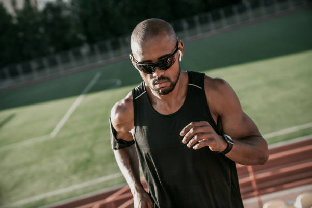 primo piano di atleta maschio con occhiali da sole e auricolari che corrono su per le scale di uno stadio - weight scale dieting weight loss foto e immagini stock