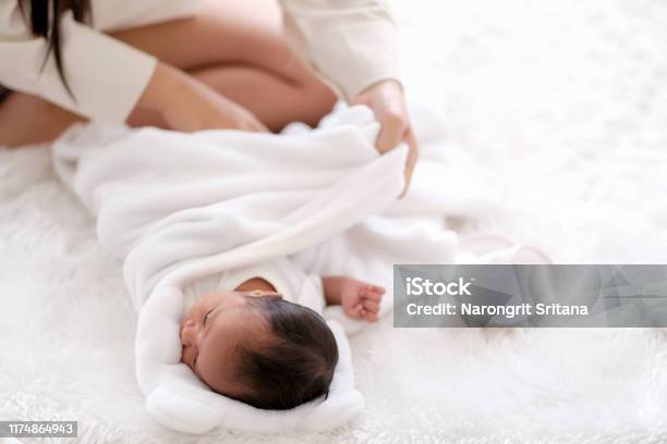 Newborn Baby Was Swaddling With White Cloth By Her Mother And The Activity Is On Bed Stock Photo - Download Image Now