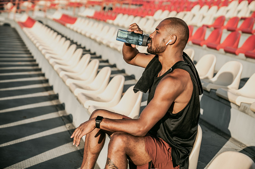 Portrait of athletic man drinking water after training at home