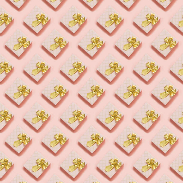 Pink gift boxes with golden ribbon on pastel pink surface. Top view. Seamless pattern. Flat lay style. Celebration anniversary background.