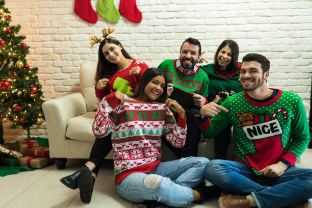 freunde in hässlichen pullover feiern weihnachten zusammen zu hause - weihnachtspullover stock-fotos und bilder