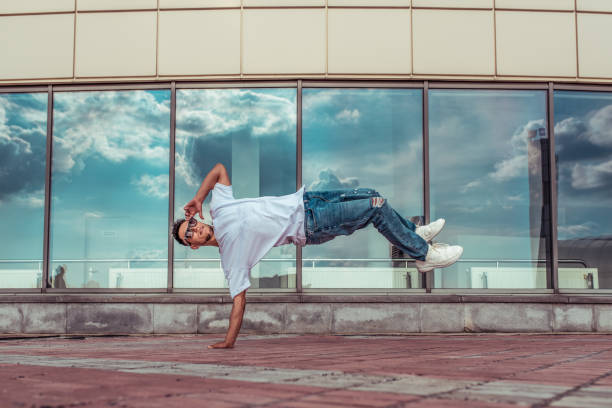 istock Young stylish man window cloud background, flying air on one hand, guy dancer, summer city, dancing break dance, healthy fitness athlete life style, white T-shirt, jeans. Dancing to music. 1174866179