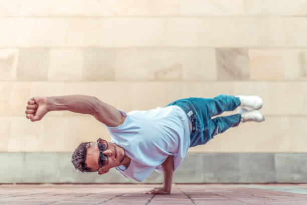 istock Young stylish athlete background wall, flight super men one arm, guy dancer, summer city dancing break dance, healthy fitness life style, shirt jeans. Dancing music. Performs public. Free space text. 1174866827