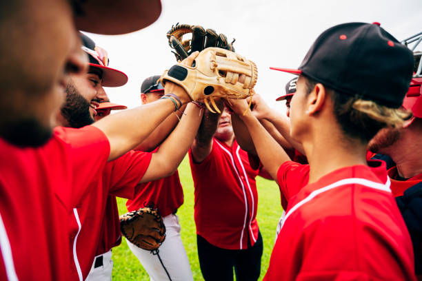 Baseball team coach and players raising gloves for high-five Young Hispanic baseball team and coach raising gloves for motivational high-five before game starts. baseball uniform photos stock pictures, royalty-free photos & images