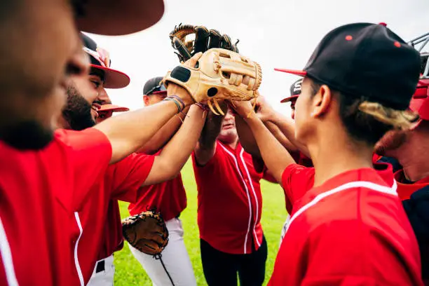 Photo of Baseball team coach and players raising gloves for high-five