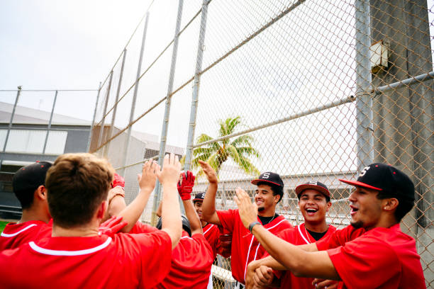 i trionfanti giocatori di baseball ispanici festeggiano con i cinque migliori - high school baseball foto e immagini stock