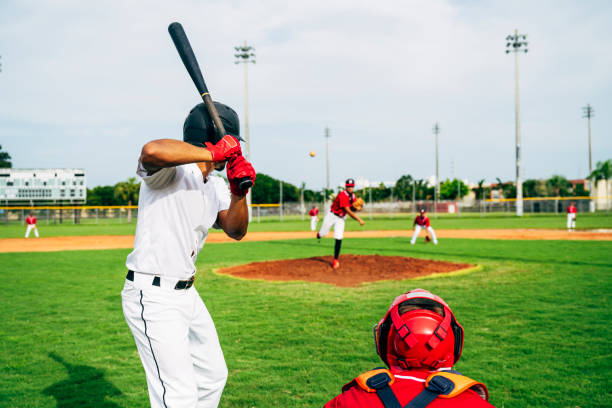 Rear view of baseball batter and catcher watching the pitch Rear view of Hispanic baseball player waiting in batting stance and watching the pitcher’s delivery of the ball. face guard sport photos stock pictures, royalty-free photos & images