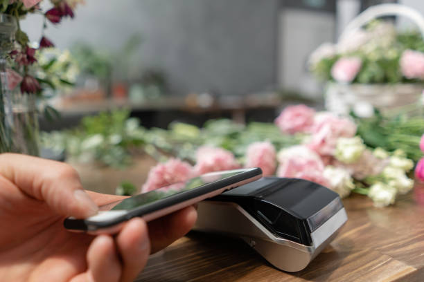istock Concept contactless payment. Making payment with smartphone and pos terminal, printed check. Floral shop concept . Flowers delivery 1174868500