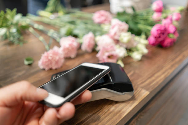 istock Concept contactless payment. Making payment with smartphone and pos terminal, printed check. Floral shop concept . Flowers delivery 1174868569